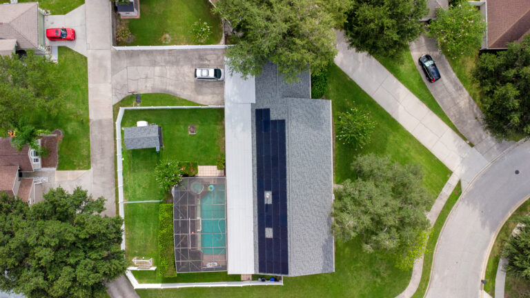overhead aerial view of black solar panels on a longwood home with a pool