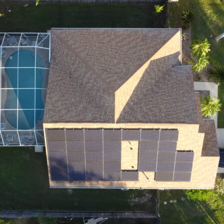 aerial view of a Port Orange solar install on the roof of a home with a pool in the backyard.